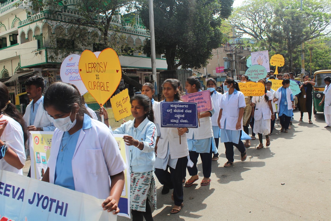 Volunteers and public carrying Shantha Jeeva Jyothi banner during World Leprosy Day public rally